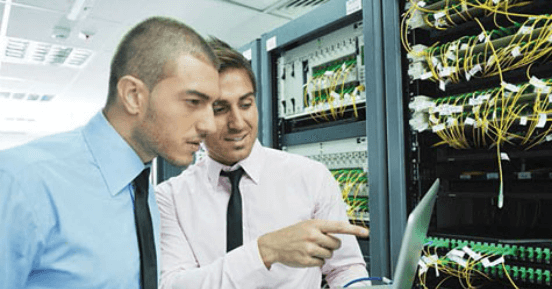 two men looking at information next to server
