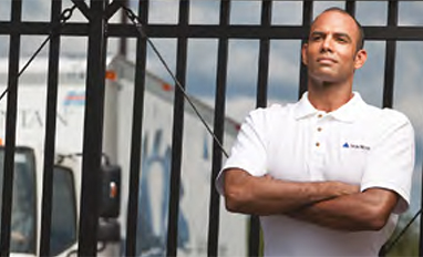 A man in an Iron Mountain polo shirt leaning against a fence with an Iron Mountain truck in the background