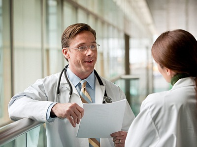 doctor holding sheet of paper talking to other doctor