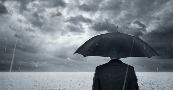 Best Practices for Business Continuity and Disaster Recovery Planning During Hurricane Season- A man with an umbrella facing the storm