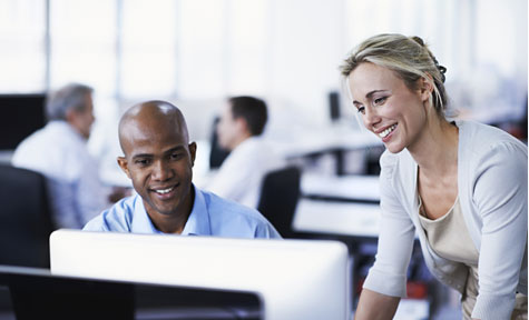 man and woman smiling at a computer screen