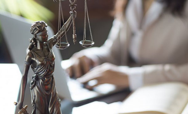 The Legal Ramifications of a Data Breach - Lady Justice with businesswomen typing | Iron Mountain