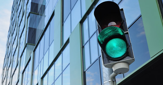 Egy kék üveg épület a háttérben és az elején egy közlekedési lámpa van beállítva, zöld lámpákkal